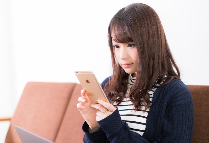 スマホで恋活アプリを使う20代前半女性